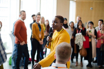 Smiling female speaker with microphone on stage