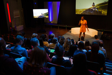 Female speaker on stage talking to audience