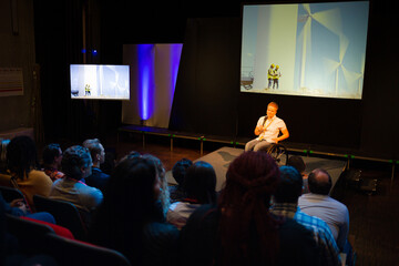 Attentive audience listening to female speaker in wheelchair on stage