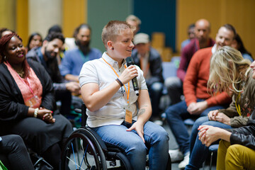 Audience watching male speaker in wheelchair talking on stage