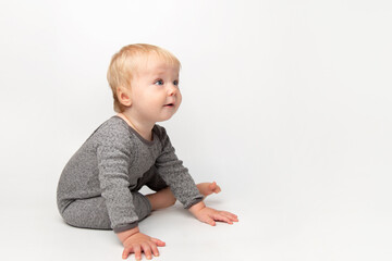 Cute small caucasian toddler baby boy child crawl on white studio floor. Smiling little infant kid wearing a yellow t-shirt explore world. Childcare and upbringing concept.