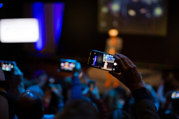 Fototapeta na wymiar Audience watching male speaker with virtual reality simulator glasses on stage
