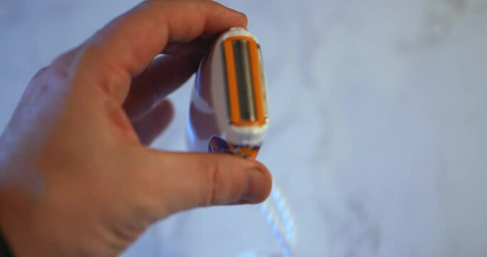 Little handheld electric razor getting plastic top cap flipped off and turned to camera by white caucasian hand. In Cinema 4k (4096x2160) 30fps slowed from 60fps.