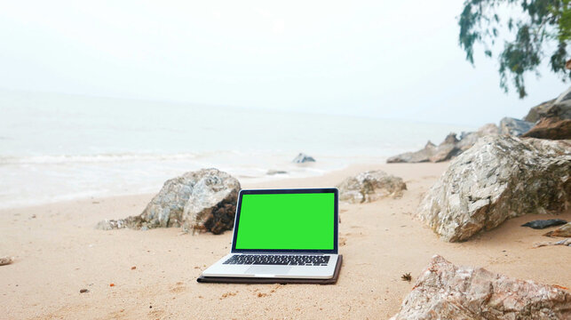 laptop on the beach, keylight green background.