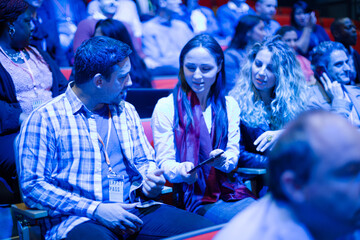 Man and woman with smart phone in conference audience