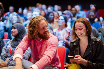 Man and woman with with smart phone in conference audience