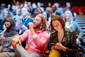 Man and woman with with smart phone in conference audience