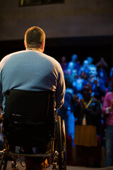 Speaker in wheelchair on stage talking to conference audience