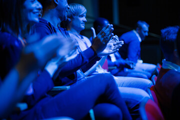 Audience clapping in dark room