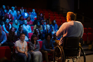 Speaker in wheelchair on stage talking to conference audience