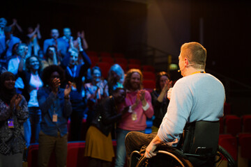 Speaker in wheelchair on stage talking to conference audience