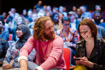 Man and woman with with smart phone in conference audience