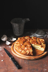 Cut Apple Pie on a Wooden Plate with a Knife and Some Egg Shells Lying Around