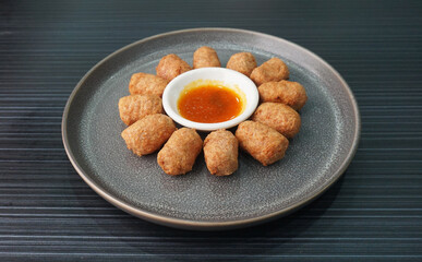 deep fried mini hot dog sausage luncheon meat with spicy sauce on dark grey wood background asian dim sum halal food restaurant cuisine banquet menu for cafe