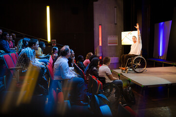 Audience watching male speaker in wheelchair talking on stage