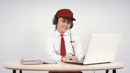 Elementary school asian girl listening on headphones while studying isolated on white background