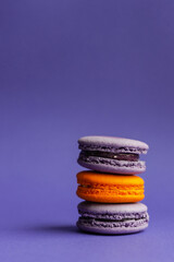 Multicolored macarons on a purple background. French dessert for Halloween. Almond flour baked goods.