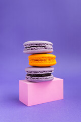 Purple and orange macaroons on a pedestal. French dessert for Halloween. Almond flour baked goods.