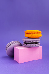 Purple and orange macaroons on a pedestal. French dessert for Halloween. Almond flour baked goods.