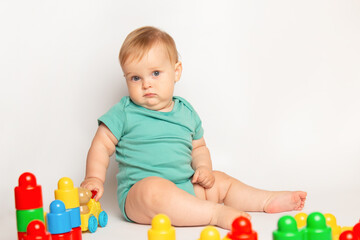 Obraz premium Kid playing with colorful educational constructor blocks. Little boy with creative toys. games for young children. Baby on white background. development of fine motor skills of children concept