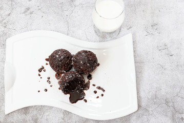 Chocolate muffins on a white plate. Sprinkled with chocolate and coconut on top. Homemade fluffy and juicy chocolate cakes. On a gray background