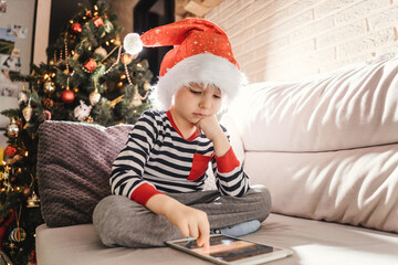 Boy play on tablet near christmas tree