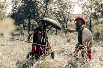 Battle with spear and sword between two ancient warriors on meadow.