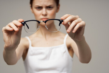 disgruntled woman glasses in the hands of astigmatism light background