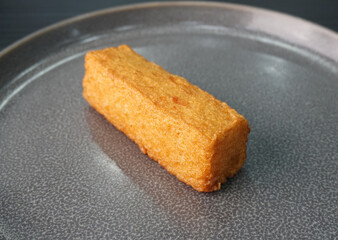 deep fried long golden stick salmon fish seafood paste cake on dark grey wood background dim sum halal menu
