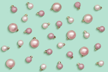 Pink Christmas balls isolated on light green background
