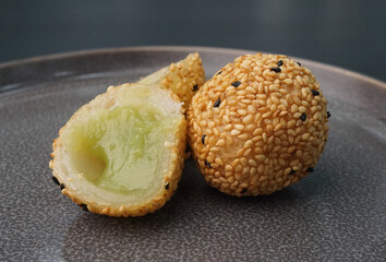 deep fried golden crispy sesame ball wrapped with sweet pandan lotus paste lava dessert on dark grey wood background dim sum menu