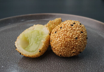 deep fried golden crispy sesame ball wrapped with sweet pandan lotus paste lava dessert on dark grey wood background dim sum menu