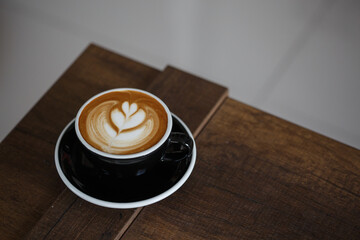 Black cup of coffee latte on wooden table.