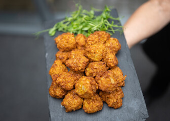 Delicious platter of Asian onion bhaji starter food snacks at wedding reception. On slate held by waitress closeup of fresh appetiser food cooked.