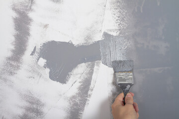 Paint the wall in the house with a brush with gray paint, repair yourself