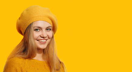   Autumn portrait beautiful happy smiling young woman wearing a french yellow beret on yellow background.