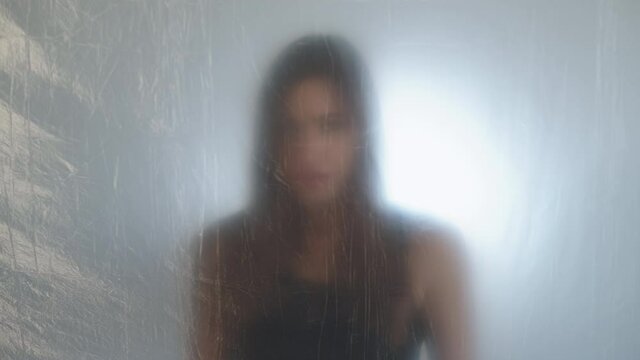 Trapped woman. Freedom deprivation. Claustrophobia disorder. Isolation despair. Defocused anxious choking out of breath girl behind plastic wrap on light out of focus background.