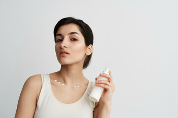 brunette with lotion in hands cosmetics skin care light background