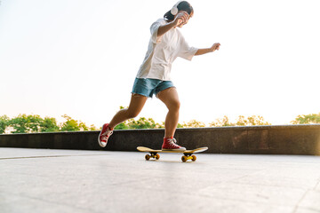 Happy young asian woman riding on a skateboard © Drobot Dean