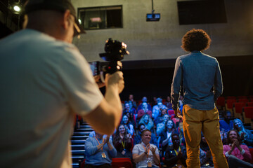 Man filming speaker and audience