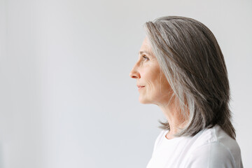 Grey senior woman in t-shirt looking aside while posing in profile