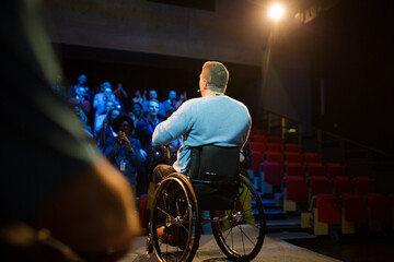 Audience watching male speaker in wheelchair talking on stage