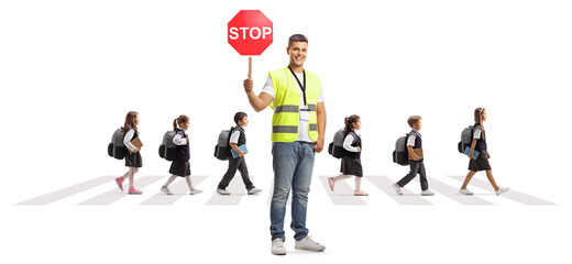 Man with a stop traffic sign standing in front of schoolchildren walking on a zebra crossing