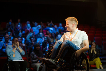Female speaker in wheelchair on stage talking to audience