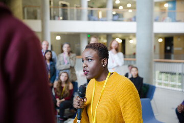Fototapeta premium Female speaker with microphone talking to audience