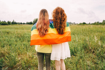 Homosexual couple holding lgbt flag, rear view.