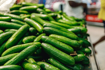 Pile of fresh cucumbers on counter in supermarket