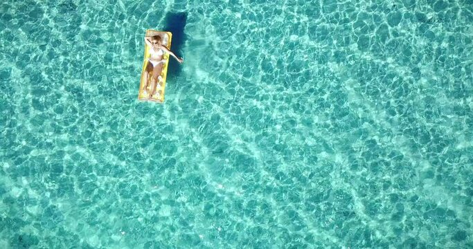 Happy tourist woman enjoy colorful mattress lilo in transparent amazing sea water viewed from vertical drone flight composition - happy female people enjoy summer holiday vacation and beach