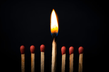 Burning match on dark black background. Difference and uniqueness concept.