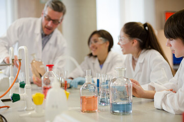 Male teacher and students conducting scientific experiment in laboratory classroom